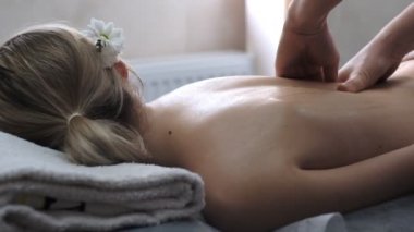 Bir masör genç bir kadına profesyonel sırt masajı yapar..