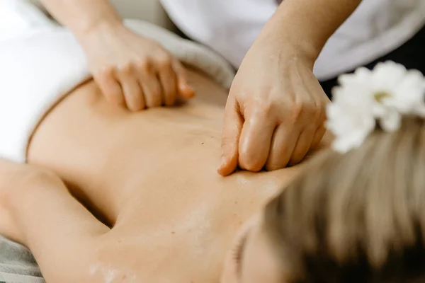 Massagista fazendo massagem nas costas para a mulher jovem . — Fotografia de Stock