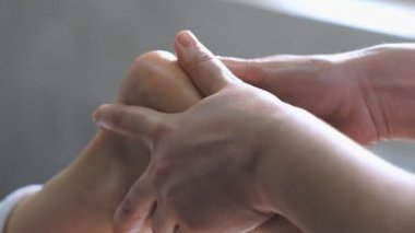 Profesyonel masaj terapisti genç bir kadına ayak masajı yapar.