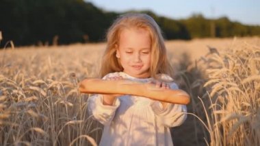Buğday tarlasında taze ekmek tutan neşeli kız, mutluluk.