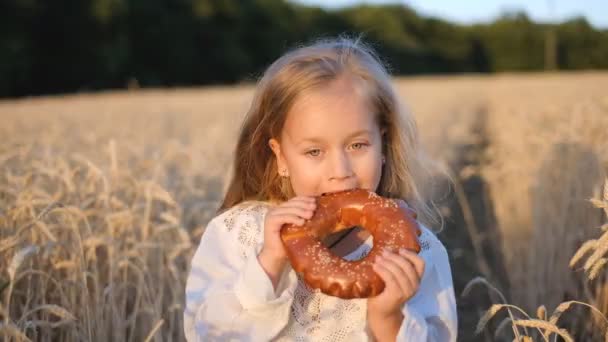 Vidám lány tart egy friss zsemlét a búzamezőn, boldogság. — Stock videók