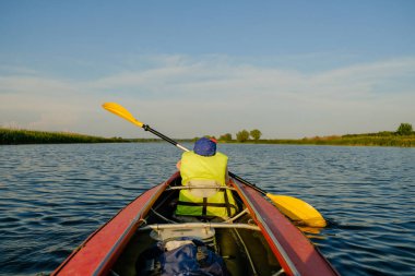 Küçük bir çocuk yazın nehirde kano yapar ve kürek çeker. Çocuk nehirde bir teknede yüzüyor..
