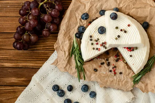 Una Testa Formaggio Piatto Bianco Giace Sul Tavolo Con Mirtilli — Foto Stock