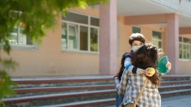 Anne oğluna okula kadar eşlik eder. Bir anne okula girmeden önce oğlu için koruyucu bir maske takar. Okul yılının başlangıcı..