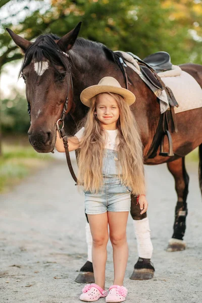 L'amitié d'un enfant avec un cheval. Traiter l'autisme avec un cheval. Interaction d'une fille autiste et d'un cheval. Marcher un enfant avec un cheval à l'automne. — Photo