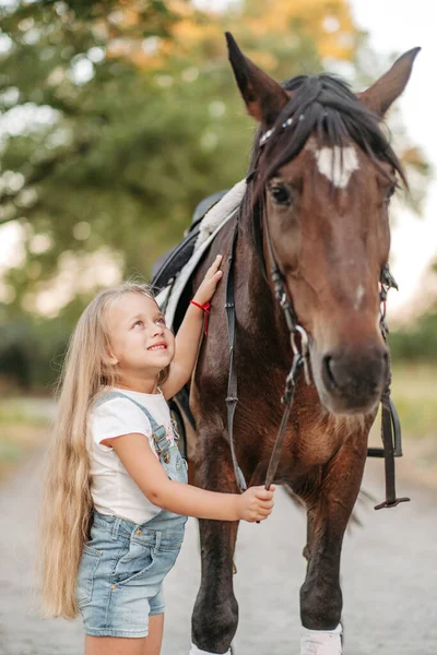 L'amitié d'un enfant avec un cheval. Traiter l'autisme avec un cheval. Interaction d'une fille autiste et d'un cheval. Marcher un enfant avec un cheval à l'automne. — Photo