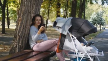 Genç bir anne parkta bir bankta oturur ve bebek arabasının yanında uyuyan bir bebekle konuşur. Bebek bebek arabasında uyuduğunda anne parkta dinlenir..