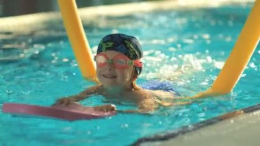 Geleceğin şampiyonu. Küçük şampiyon için yüzme eğitimi. Küçük tatlı çocuk havuzda yüzerek sağlığını güçlendiriyor..