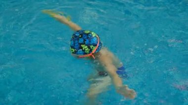 Tatlı bir çocuk yüzme ve havuza dalma alıştırması yapıyor. Sağlık promosyonu için havuza çocuk sporları.