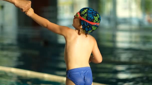 プールで小さなスポーツマンスイマーとトレーナーの成功と相互作用の概念 少年運動選手が拳でコーチを打つ — ストック動画