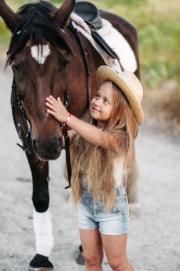 Atlı bir çocuğun arkadaşlığı. Küçük bir kız sevgiyle atını okşuyor. Sonbaharda parkta at gezdiren kızlar..