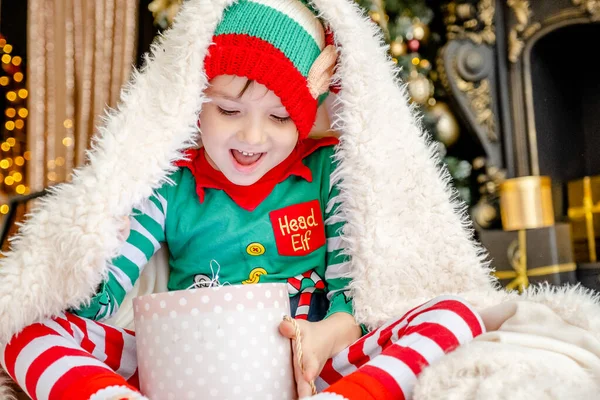 Cute Little Boy Dressed Elf Opens Christmas Present While Hiding — Stock Photo, Image