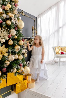Güzel sarışın bir kız Noel 'den önce evde bir ağaç süsler. Mutlu bir çocukluk. Noel 'den önce bir Noel ağacı süslemek.