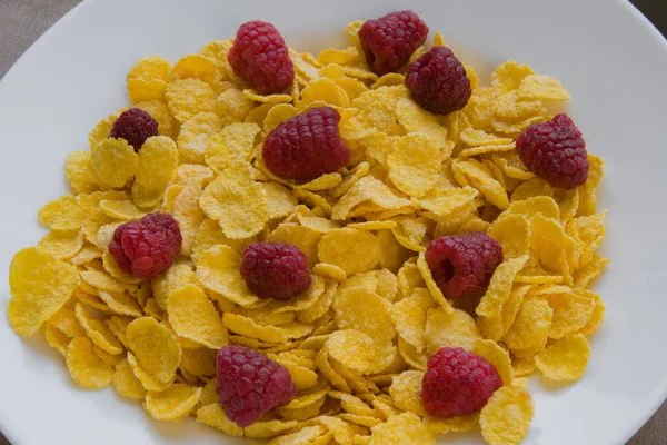 Corn flakes with fresh raspberries in a white plate