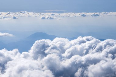 Dağların üzerindeki kabarık bulutlar uçak penceresinden görünümü