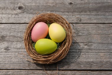 Ahşap bir arka planda yuvadaki çok renkli paskalya yumurtaları. Paskalya konsepti