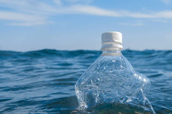 A plastic bottle floats on the surface of the water in the open sea. Ecology concept