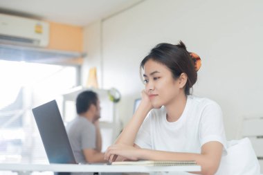 Asyalı bir iş kadını çalışıyor ve erkek arkadaşı da bulaşıcı hastalıkları önlemek için hükümet politikalarına göre evde çalışıyor..