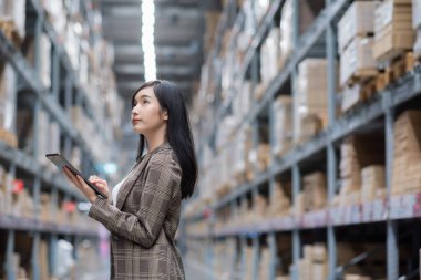 Alışveriş merkezindeki mobilya mağazasında çalışan Asyalı kadın. Tabletle mal arayan bir kız depodaki envanter seviyelerini kontrol ediyor. Lojistik kavramı