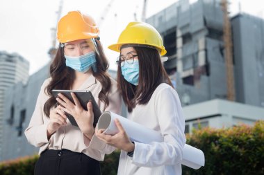 Coronavirus salgını krizi sırasında inşaat alanında çalışırken yüz maskesi ya da cerrahi maske takan çeşitli insanlar. Mühendislik konsepti.