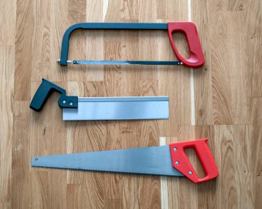 İnşaat aletleri seti, sanayi sektöründe kullanılmak üzere ahşap arka planda farklı testereler içeriyor. Kendi başlarına tamir edebilirler..