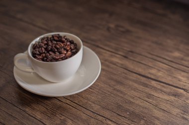 Kavrulmuş kahve çekirdekleri, bulanık arka plan ve kupa.