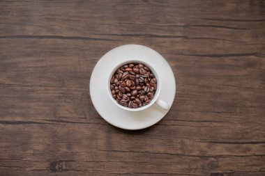 Kavrulmuş kahve çekirdekleri, bulanık arka plan ve kupa.