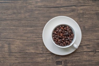 Kavrulmuş kahve çekirdekleri, bulanık arka plan ve kupa.