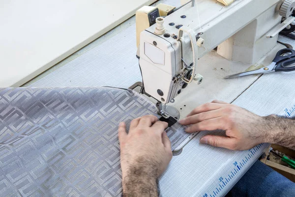 Tailor stitched seat fabrics. Close-up on man working with her sewing machine stitching a long length of fabric.