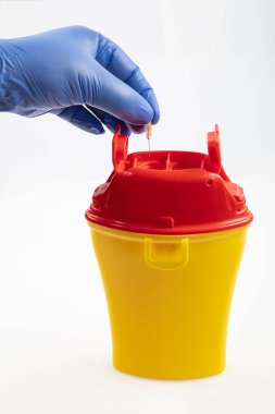Sağlık çalışanı tıbbi atık kutusuna keskin atıklar atıyor. Tıbbi atık kutusu 0,4 litre. Sarı biyolojik tehlike tıbbi kirlenmiş klinik atık konteynırı beyaz arka planda izole edildi.