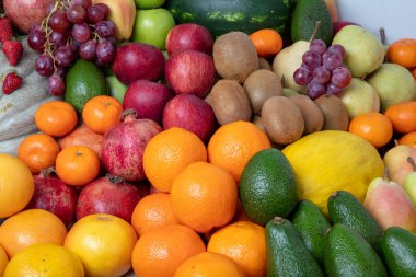 Stüdyoda çeşitli meyveler çekiliyor: mandalinalar, nar, portakal, elma, armut, üzüm, mango,... hepsi raflarda dizilmiş çekici ve göz alıcı görünüyor..