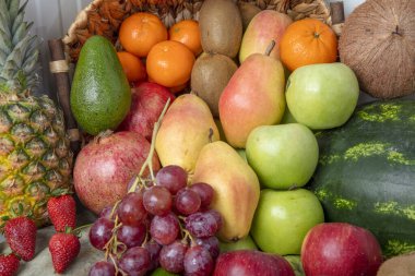 Stüdyoda çeşitli meyveler çekiliyor: mandalinalar, nar, portakal, elma, armut, üzüm, mango,... hepsi raflarda dizilmiş çekici ve göz alıcı görünüyor..