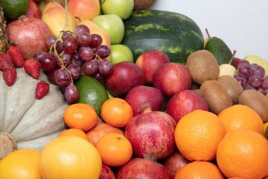 Stüdyoda çeşitli meyveler çekiliyor: mandalinalar, nar, portakal, elma, armut, üzüm, mango,... hepsi raflarda dizilmiş çekici ve göz alıcı görünüyor..