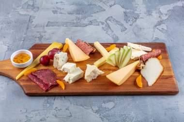 Peynir tabağı manzaralı. Çeşit çeşit peynirli Camembert peyniri, Brie peyniri, Parmesan peyniri, keçi. Sosis, pastırma, üzüm, incir, elma ve kayısılarla servis edilir..