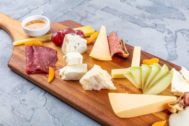 Peynir tabağı manzaralı. Çeşit çeşit peynirli Camembert peyniri, Brie peyniri, Parmesan peyniri, keçi. Sosis, pastırma, üzüm, incir, elma ve kayısılarla servis edilir..