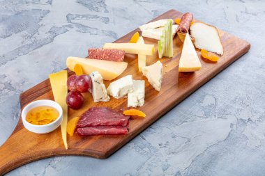 Peynir tabağı manzaralı. Çeşit çeşit peynirli Camembert peyniri, Brie peyniri, Parmesan peyniri, keçi. Sosis, pastırma, üzüm, incir, elma ve kayısılarla servis edilir..