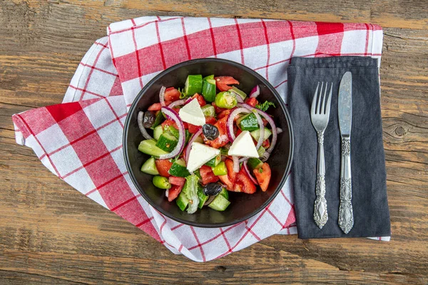 Mediterranean Salad (Greek salad) with fresh vegetables, feta cheese and black olives. Top view.