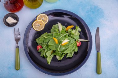 Arugula salatası. Parmesan peynirli roket salatası, limon, zeytinyağı ve ahşap arka planda baharatlar. Vejetaryen yemeği.