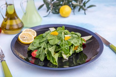 Arugula salatası. Parmesan peynirli roket salatası, limon, zeytinyağı ve ahşap arka planda baharatlar. Vejetaryen yemeği.