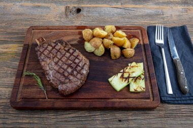 Domatesli ızgara biftek, et kesme tahtasında soslu sarımsak..