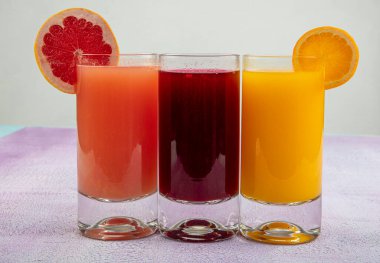 Beyaz ahşap arka planda ferahlatıcı narenciye kokteyli. Antioksidan Nar Suyu, Portakal Suyu, Greyfurt Suyu.