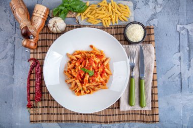 Acı soslu arrabiata soslu makarna. Klasik İtalyan penne arrabiata fesleğenli ve taze rendelenmiş pecorino peynirli ahşap masa..