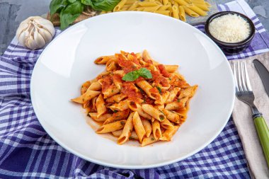 Acı soslu arrabiata soslu makarna. Klasik İtalyan penne arrabiata fesleğenli ve taze rendelenmiş pecorino peynirli ahşap masa..