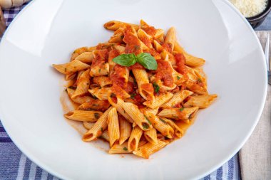Acı soslu arrabiata soslu makarna. Klasik İtalyan penne arrabiata fesleğenli ve taze rendelenmiş pecorino peynirli ahşap masa..