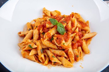 Acı soslu arrabiata soslu makarna. Klasik İtalyan penne arrabiata fesleğenli ve taze rendelenmiş pecorino peynirli ahşap masa..