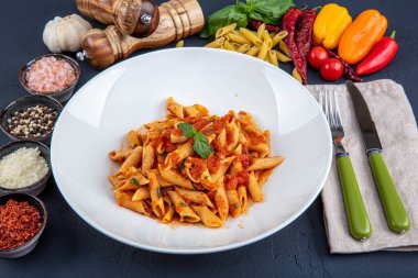 Acı soslu arrabiata soslu makarna. Klasik İtalyan penne arrabiata fesleğenli ve taze rendelenmiş pecorino peynirli ahşap masa..