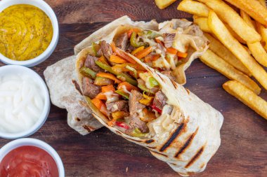 Tortilla sandviçleri taze sebzelerle sarar, kıyma yapar ve patates kızartmasıyla servis edilir. Burrito, sandviç, fajita dürümü..