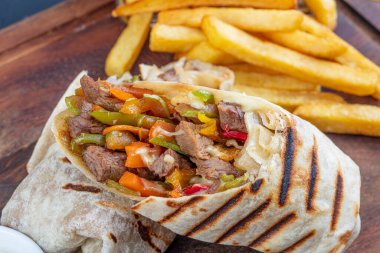 Tortilla sandviçleri taze sebzelerle sarar, kıyma yapar ve patates kızartmasıyla servis edilir. Burrito, sandviç, fajita dürümü..