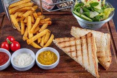 Çedar tostu, tahtanın üzerinde patates kızartmasıyla servis edilir..