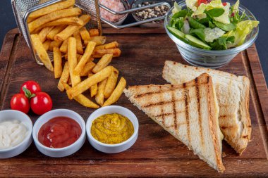 Çedar tostu, tahtanın üzerinde patates kızartmasıyla servis edilir..